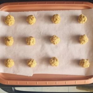 Hacer bolitas con nuestra mas para galletas veganas proteicas de avena sin gluten y ubicar en un molde con papel pergamino.