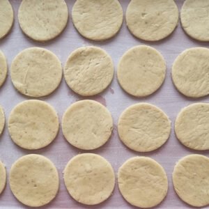Paso ocho de la preparación de nuestros alfajores veganos de maicena: Ubicar los cortes de nuestra masa en un molde enmantequillado y enharinado para hornear por 10 minutos.