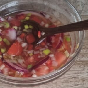 Paso 7 de la preparación de agrio ecuatoriano: Nuestro bowl con la vinagreta al que le agregamos tomates, cebolla y pimiento rojo.