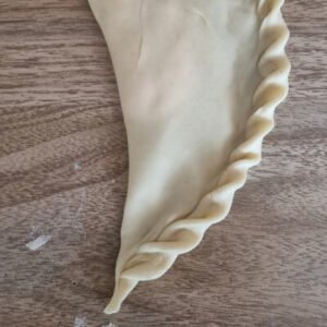 Paso 7 en la preparación de empanadas de viento veganas. Cerrar la empanada y repulgar el borde como en la imagen.