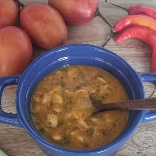 Ají criollo de la sierra ecuatoriana en un bowl azul con algunos tomates, ajíes y cebolla larga alrededor.