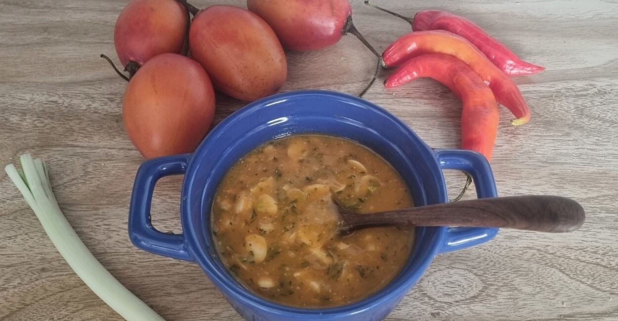 Ají criollo de la sierra ecuatoriana en un bowl azul con algunos tomates, ajíes y cebolla larga alrededor.