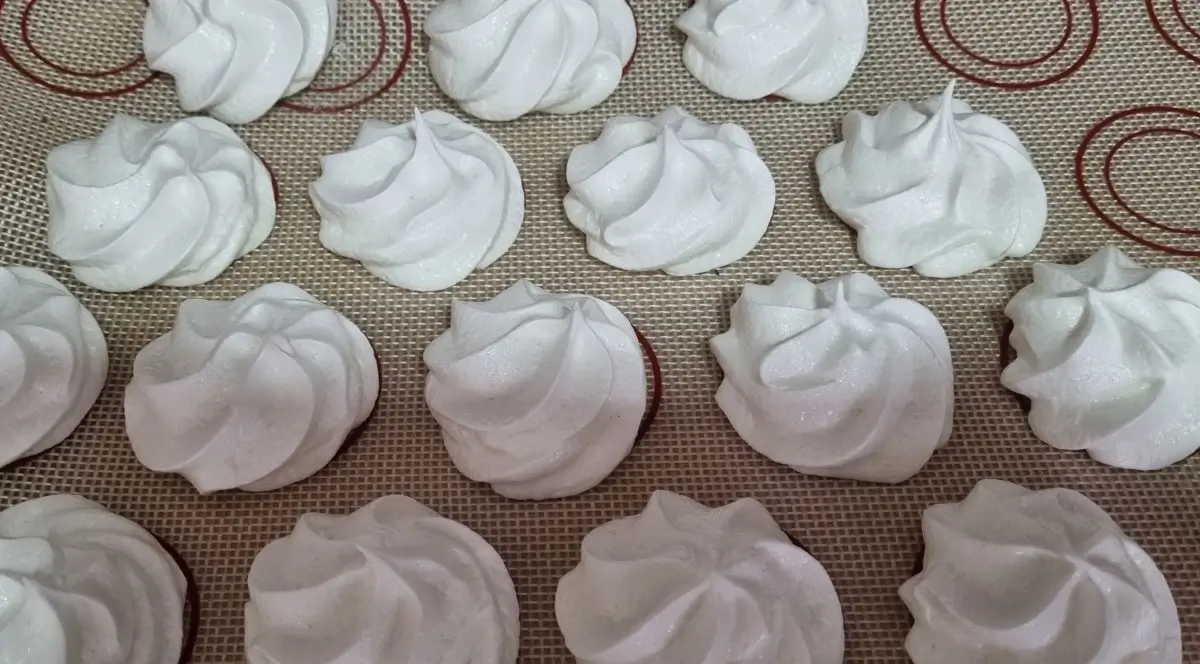 Merengues de aquafaba y otros de potatowhip en una bandeja de hornear para mostrar sus diferencias.