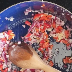 Receta Goulash vegano paso 3: Una sartén con aceite en la que el pimiento, cebolla y ajo cortados finamente están siendo sofritos.