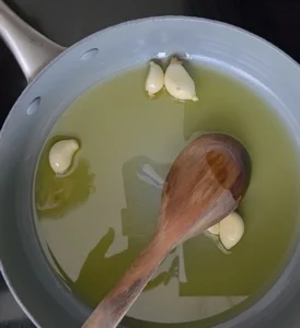 Migas pastoriles veganas de Extremadura - Receta tradicional - En una sartén o cacerola grande, colocar el aceite de oliva y los dientes de ajo enteros. Dejar aromatizar a fuego medio durante 3 a 4 minutos.